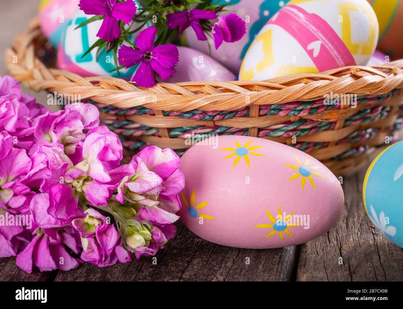 Primo piano di fiori colorati e uova di pasqua su una vecchia superficie in legno Foto Stock