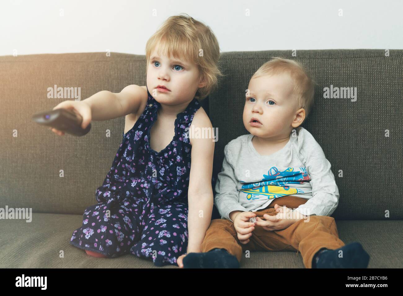 due bambini seduti sul divano e guardando la tv a casa Foto Stock