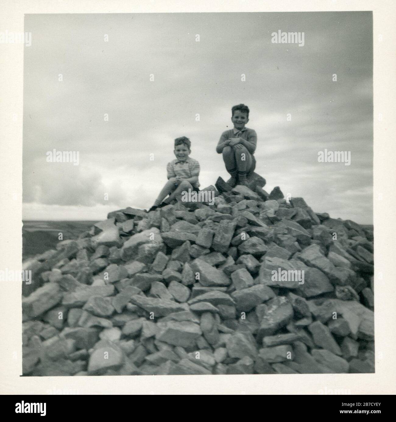 Archivio degli anni 1950 istantanea vacanza scatto di due ragazzi seduti in cima ad un grande mucchio di rocce. Trovato foto storia sociale volgare fotografia UK. Fotografo sconosciuto (collezione Richard Bradley) Foto Stock