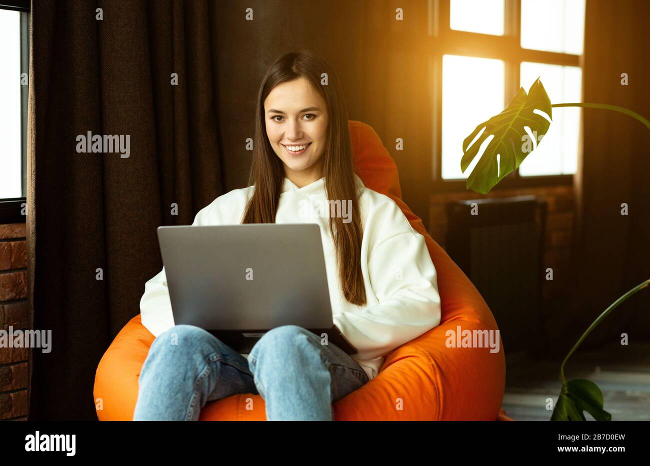 Lavoro freelance da casa. Donna millenaria in sedia a sacco Foto Stock