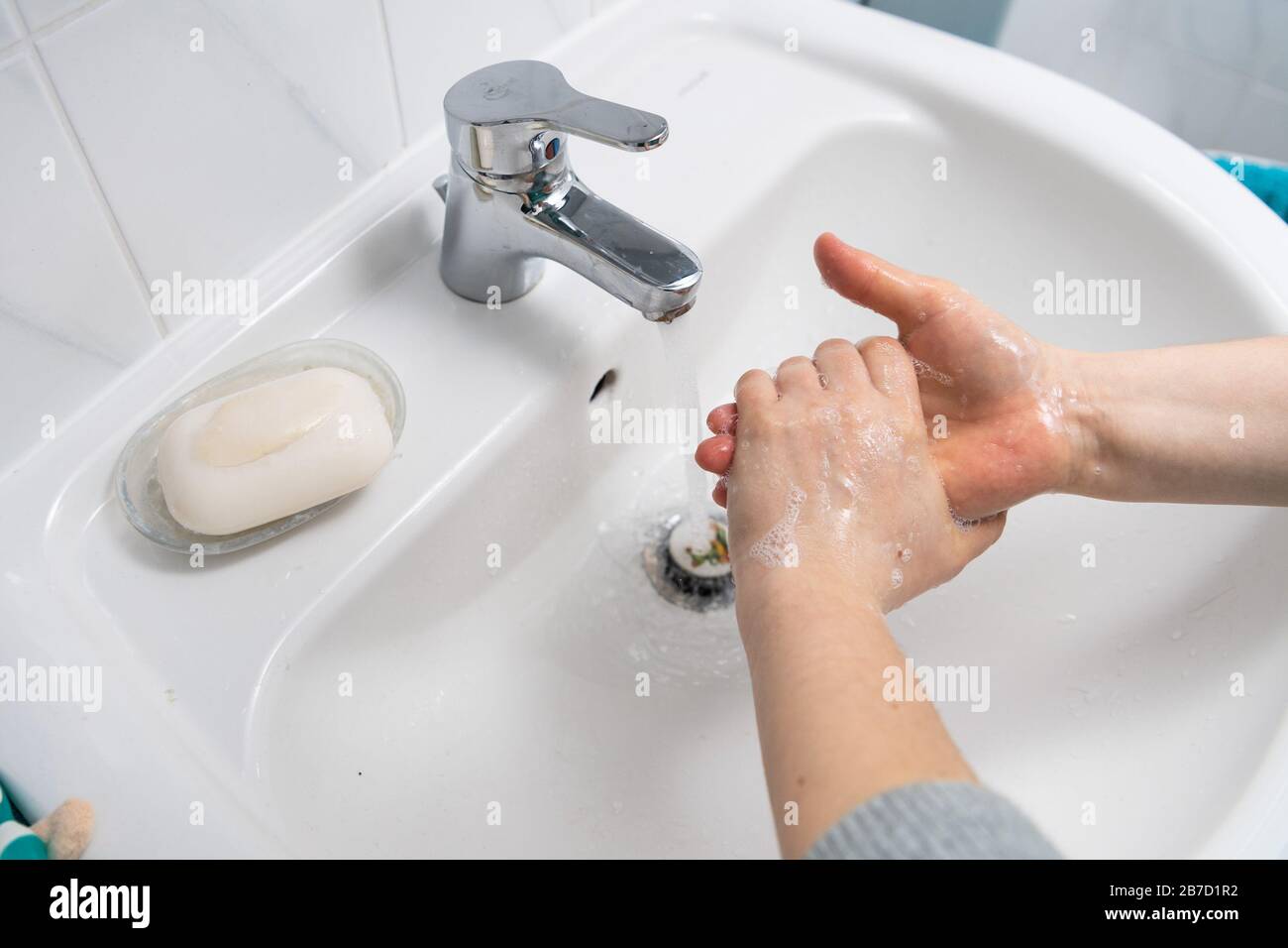 Lavando le mani con sapone in un lavandino bianco Foto Stock