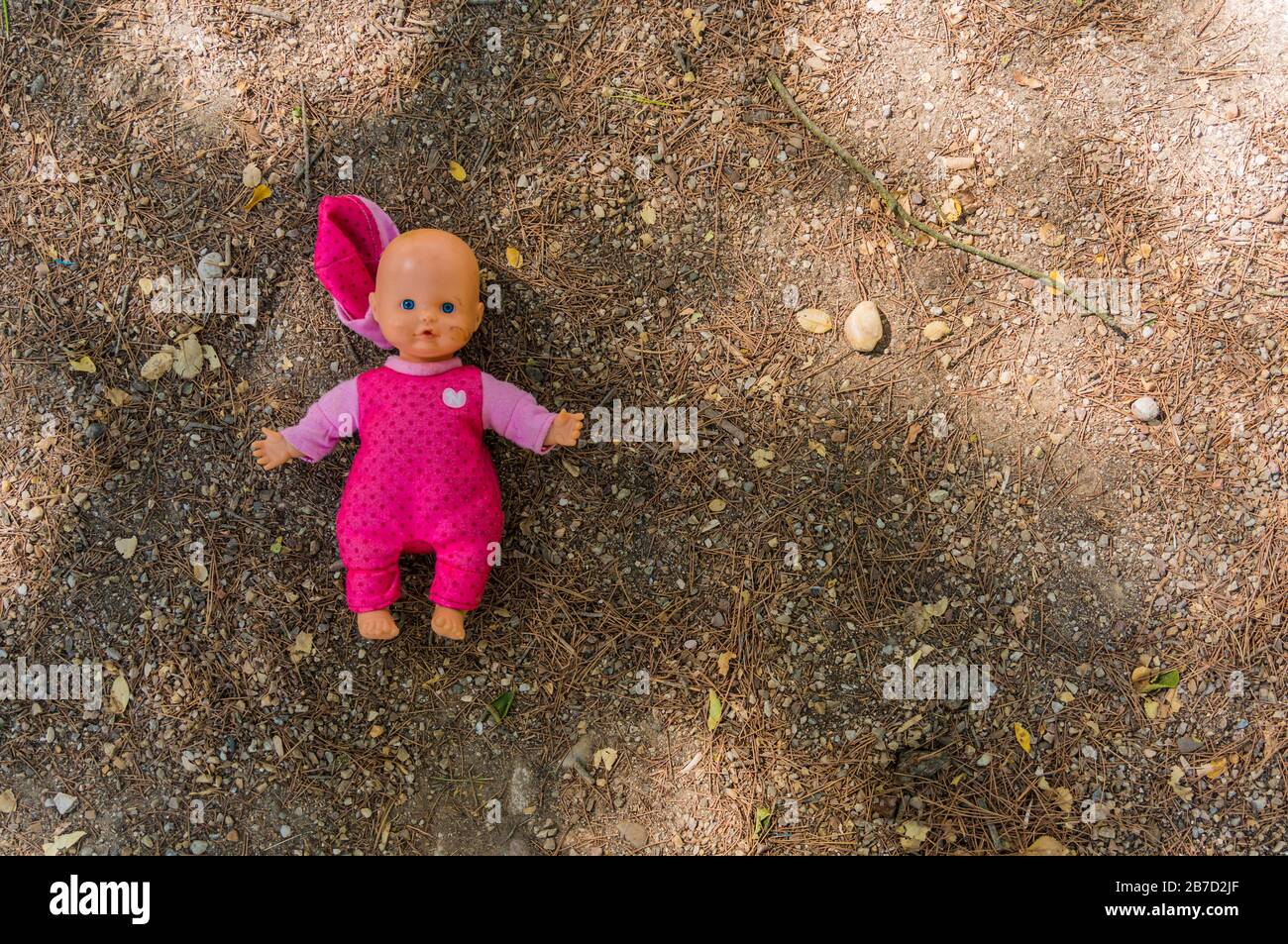 Concetto abbandonato: Bambola abbandonata a terra in un parco Foto Stock