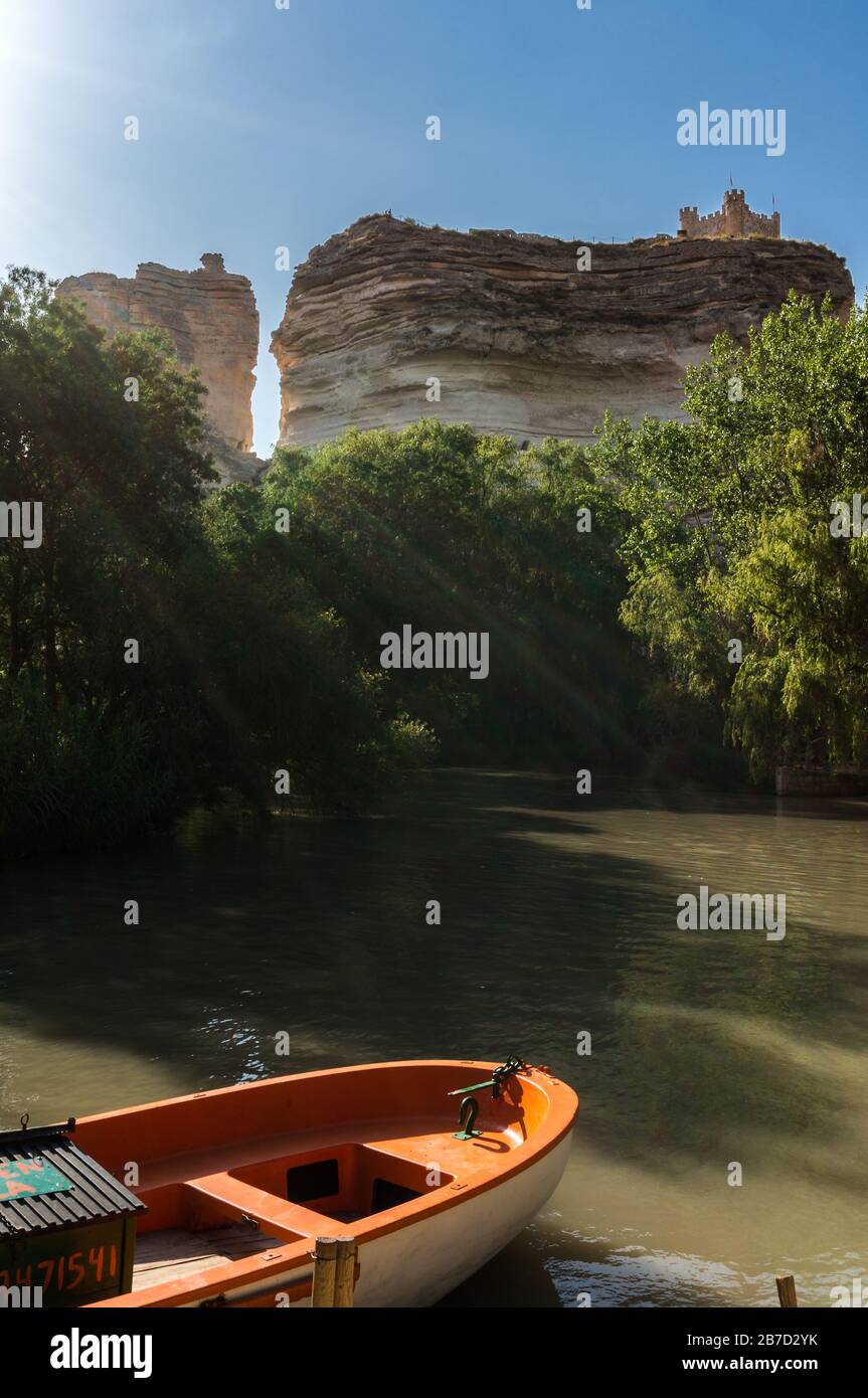 Barca sul fiume, raggi di sole e castello in cima alle rocce a Alcalá del Júcar in Albacete, Castilla la Mancha in Spagna Foto Stock