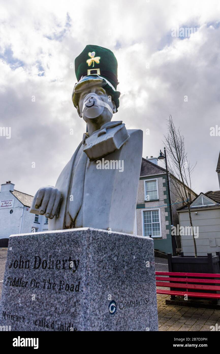Ardara, Contea di Donegal, Irlanda. 15 marzo 2020. Il busto del famoso giocatore irlandese di violino, John Doherty, è adornato con maschera e cappello che scherzano l'attuale Coronavirus, Covid-19, pandemia. La parata del giorno di San Patrizio della città è stata cancellata insieme alla maggior parte di tali parate in Irlanda. Foto Stock