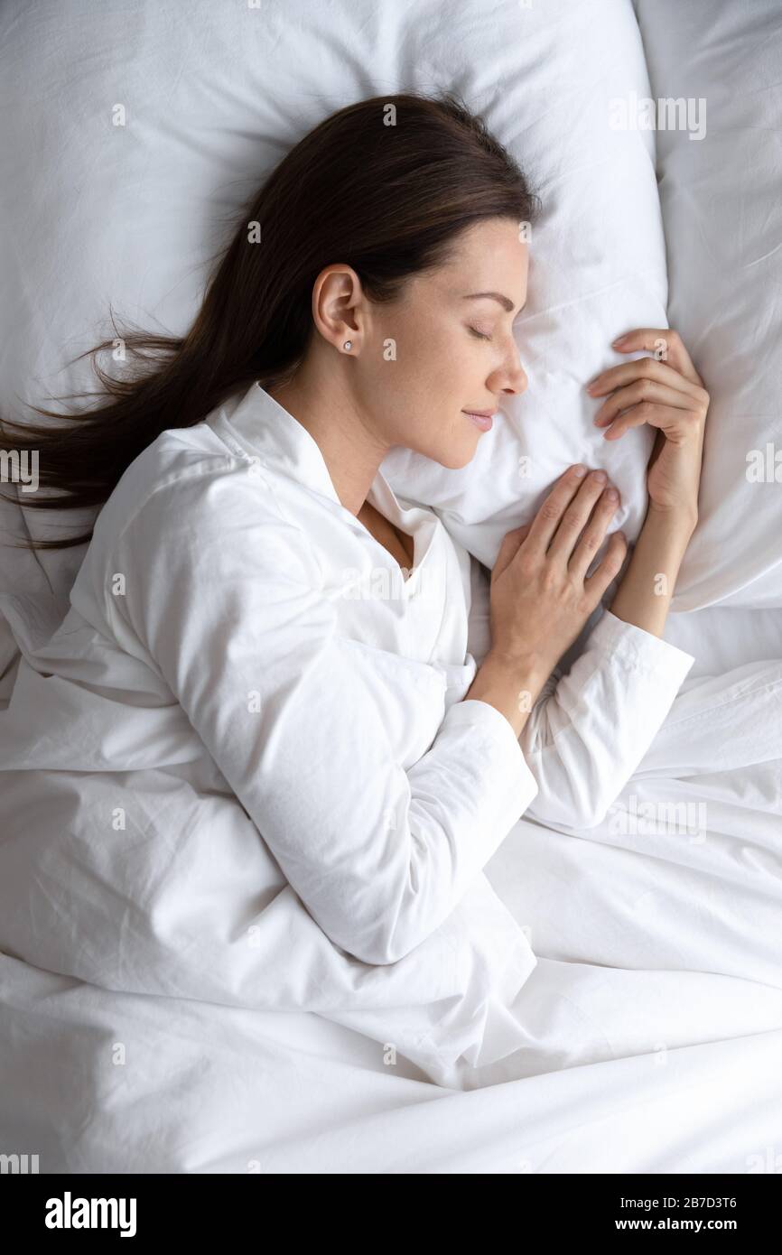 Immagine verticale tranquilla giovane donna in pajama dormire a letto. Foto Stock