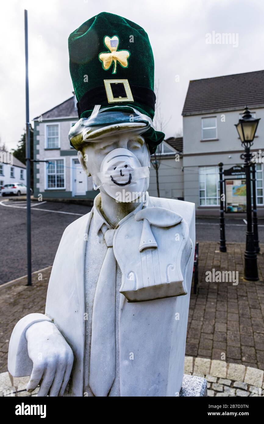 Ardara, Contea di Donegal, Irlanda. 15 marzo 2020. Il busto del famoso giocatore irlandese di violino, John Doherty, è adornato con maschera e cappello che scherzano l'attuale Coronavirus, Covid-19, pandemia. La parata del giorno di San Patrizio della città è stata cancellata insieme alla maggior parte di tali parate in Irlanda. Foto Stock