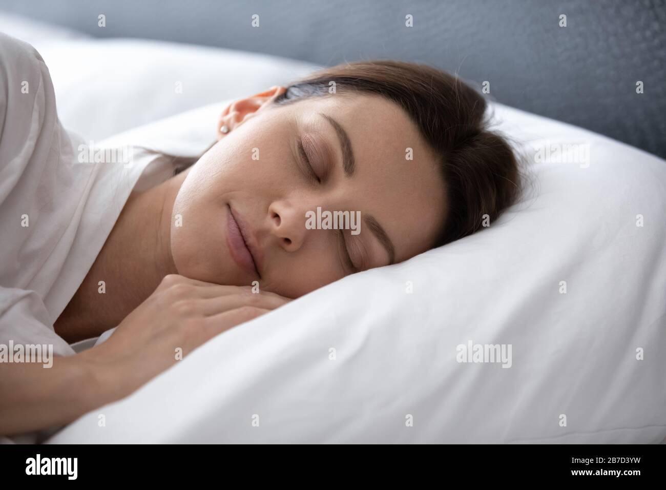 Giovane donna tranquilla godendo buon riposo notturno su morbido cuscino. Foto Stock