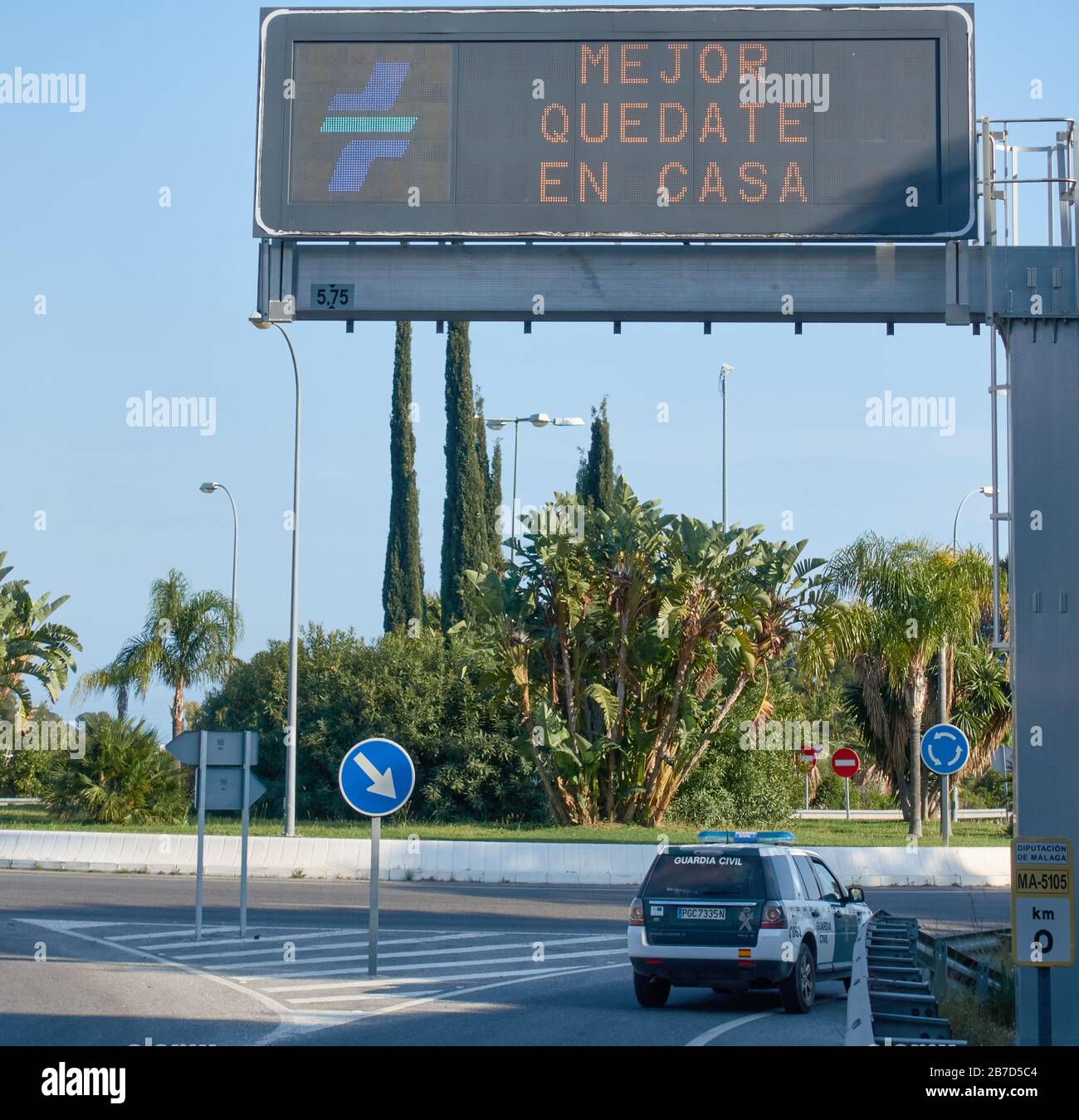 Un veicolo della Guardia civile spagnola passa sotto un cartello che suggerisce ´è´s meglio rimanere a casa´ all’inizio della pandemia del coronavirus, Malaga, Spagna Foto Stock