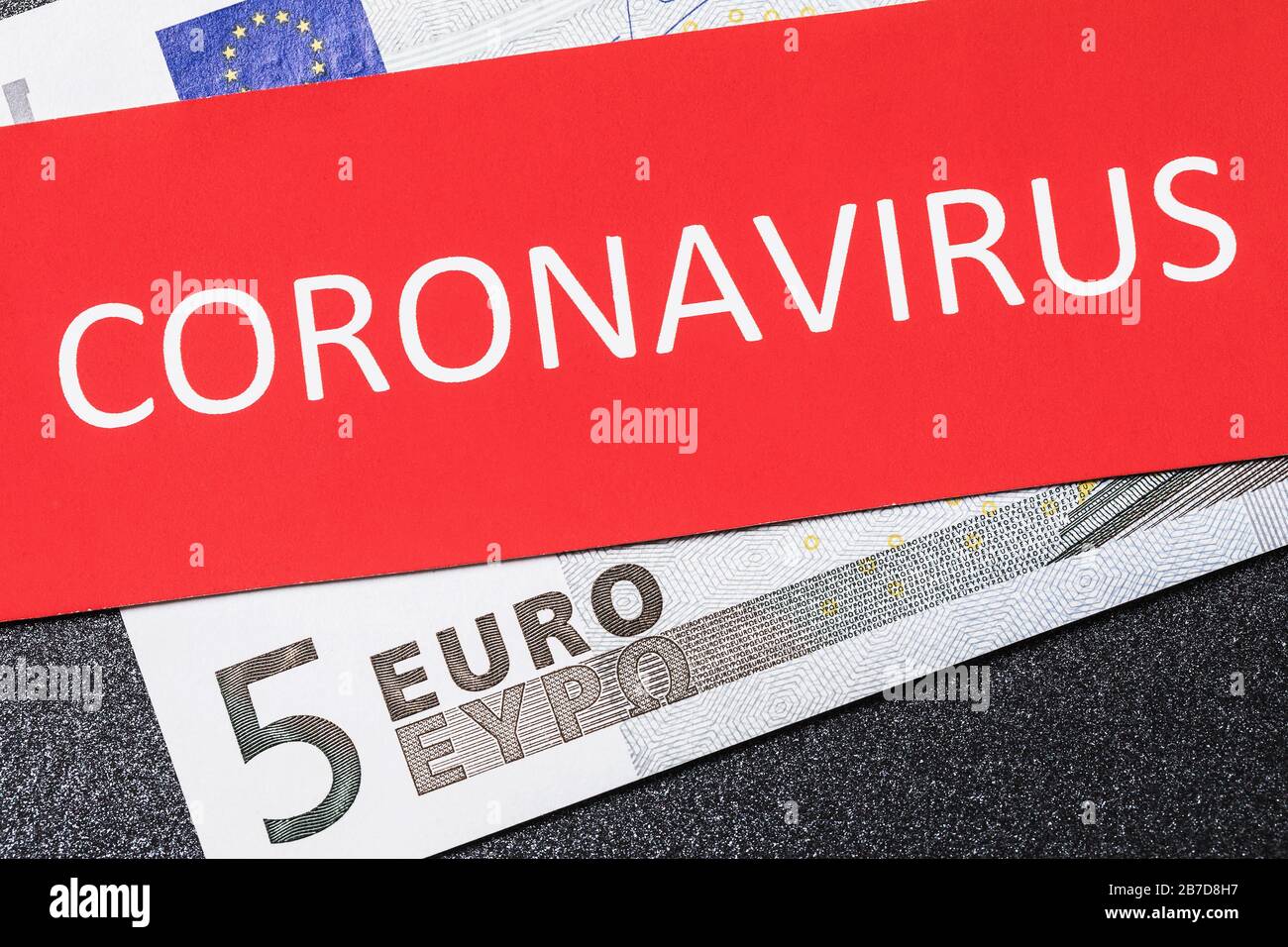 Cinque euro e un foglio con l'iscrizione, primo piano. Il concetto di effetto del coronavirus sulla moneta europea Foto Stock
