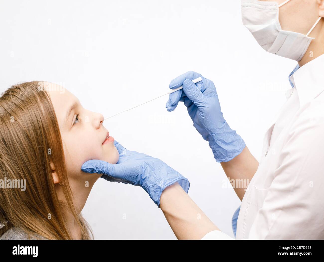Pediatra o medico che preleva il campione di test del muco nasale dal naso della ragazza di età elementare eseguendo la procedura di test del virus respiratorio Foto Stock