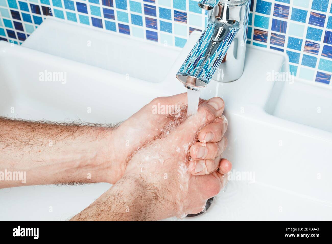 Uomo che lava le mani eseguendo le misure protettive di base contro la diffusione dell'epidermide del coronavirus Foto Stock