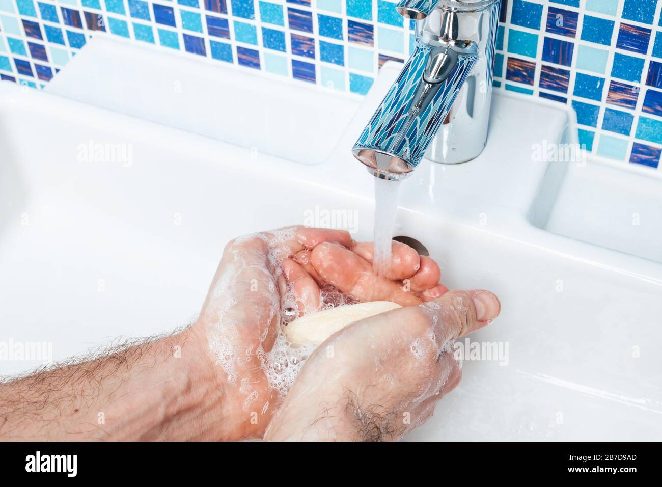 Uomo lavando le mani con sapone antibatterico e acqua che attuano le misure protettive di base contro la diffusione dell'epidermide del coronavirus Foto Stock