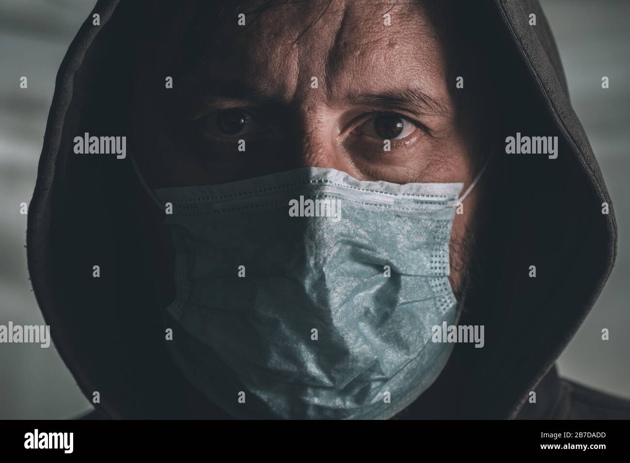 Uomo impaurito con maschera respiratoria usa e getta che copre il suo viso durante l'epidemia di virus epidemico Foto Stock