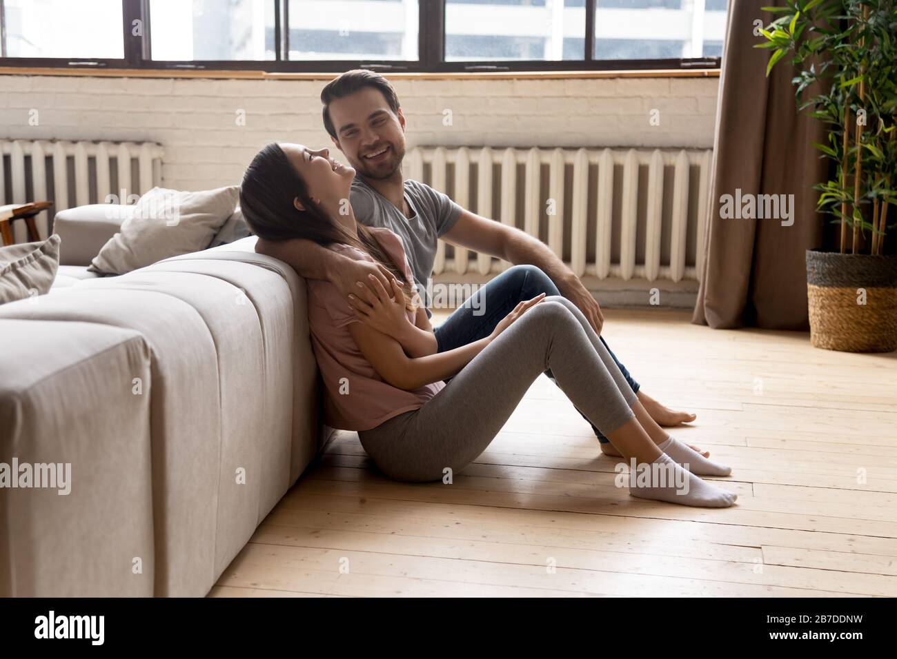 Una giovane coppia felice si rilassa sul caldo pavimento in legno Foto Stock