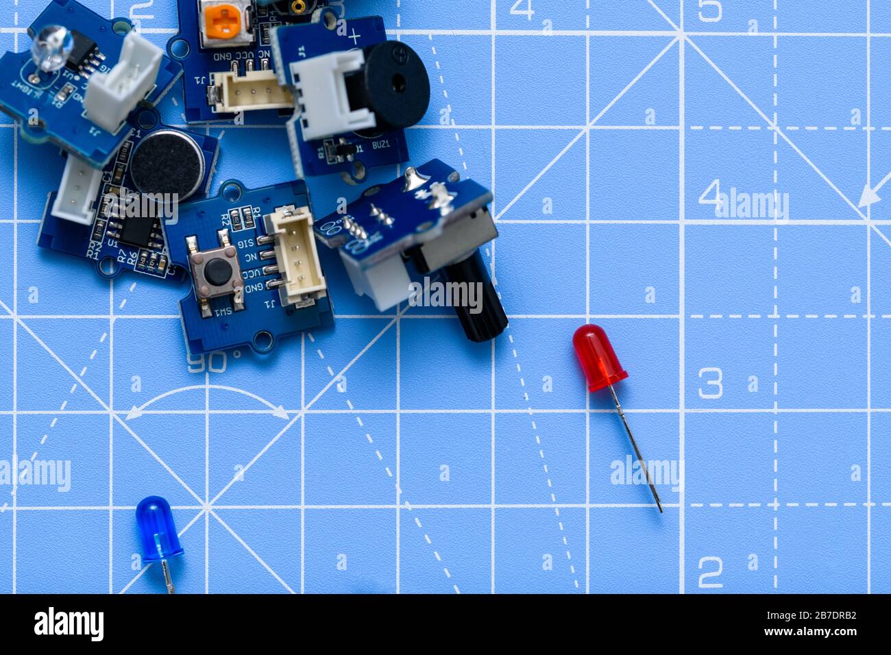 Primo piano delle schede e dei componenti elettrici a LED rosso e blu su sfondo blu. Concetto di elettronica, scienza, industria o istruzione Foto Stock