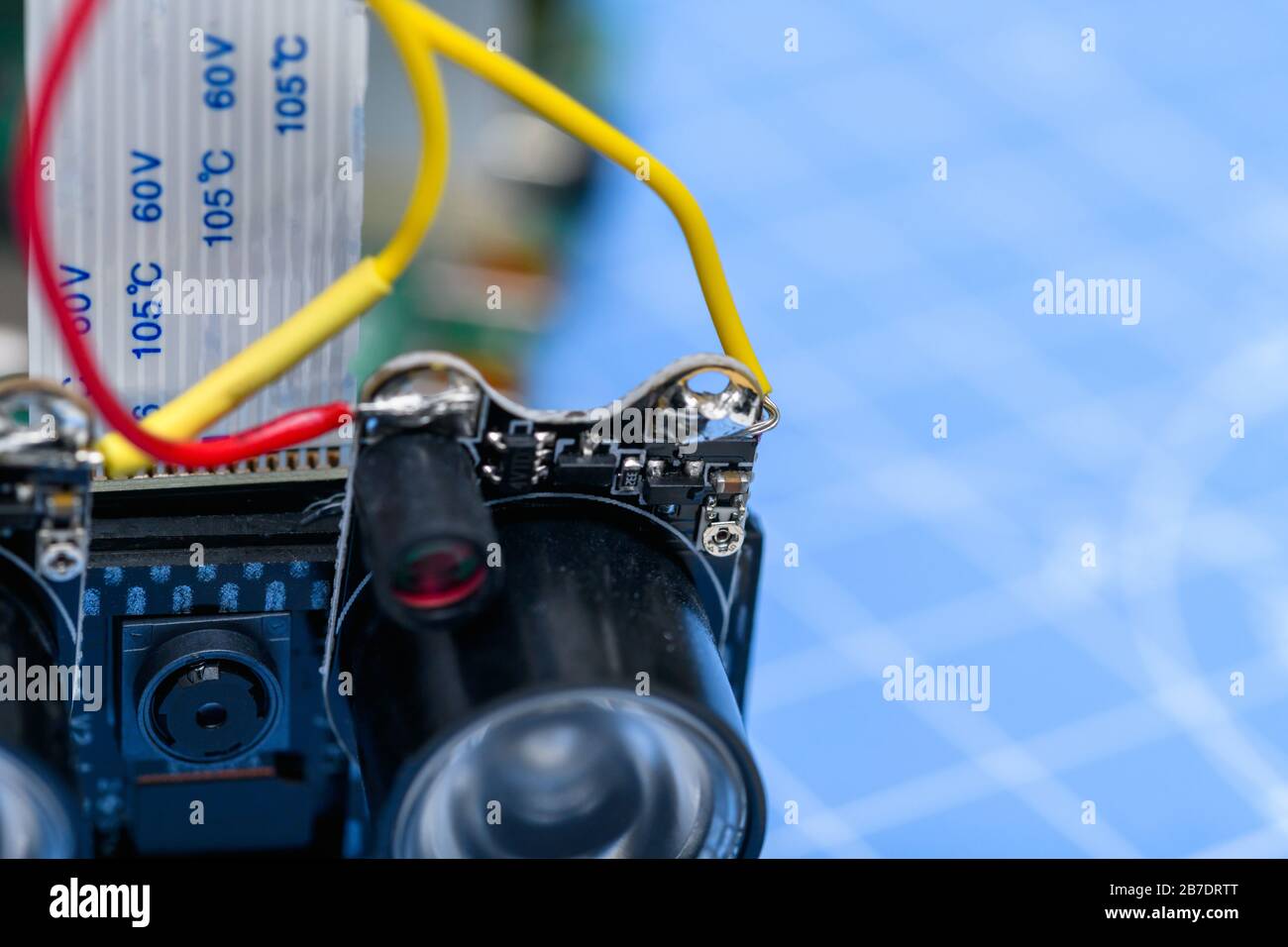 Close-ip di piccola telecamera e circuito-board con luce a infrarossi con cavo collegato su sfondo blu. Foto Stock