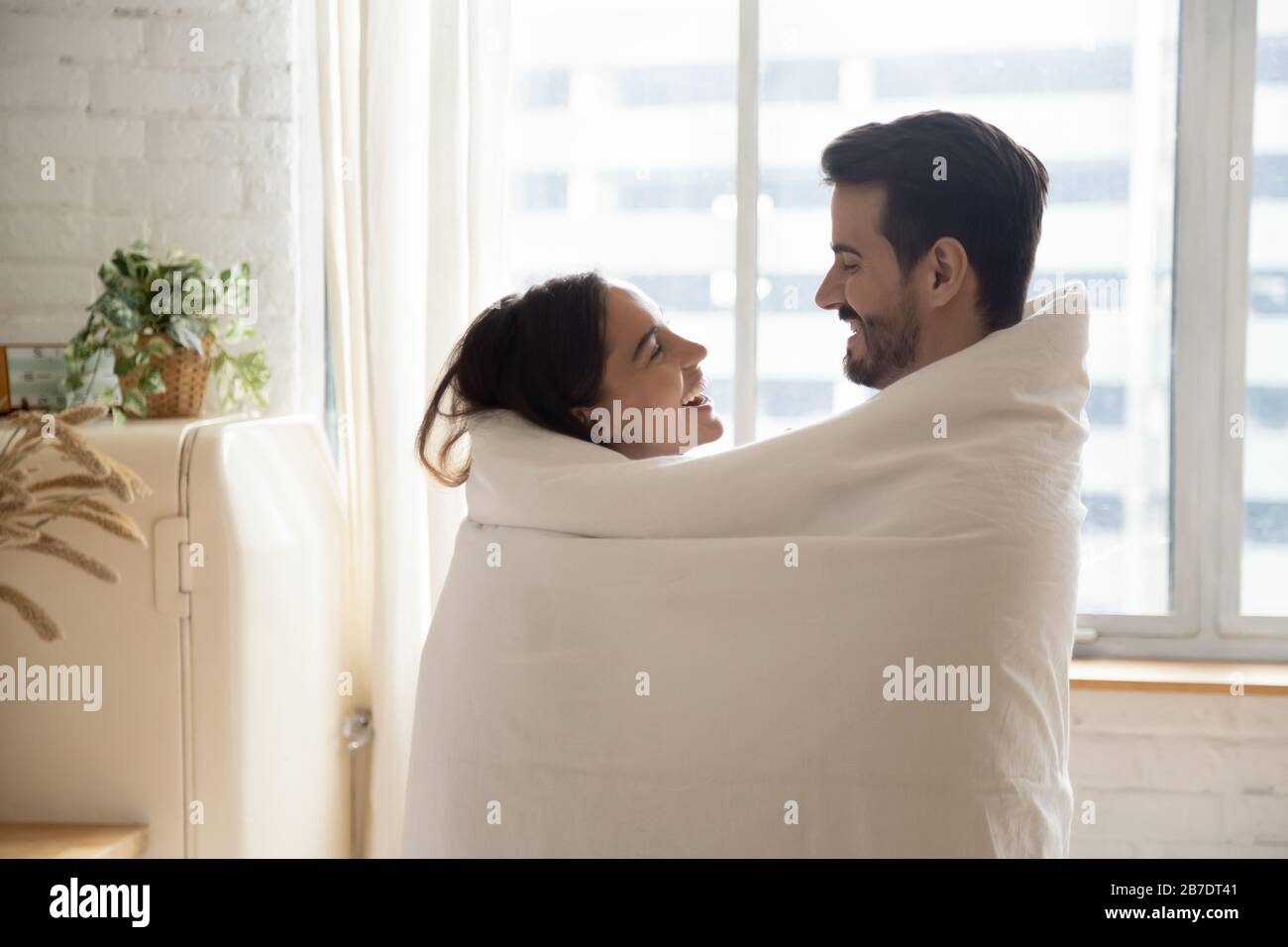 Felice coppia amorevole avvolta in coperta calda abbracciare Foto Stock