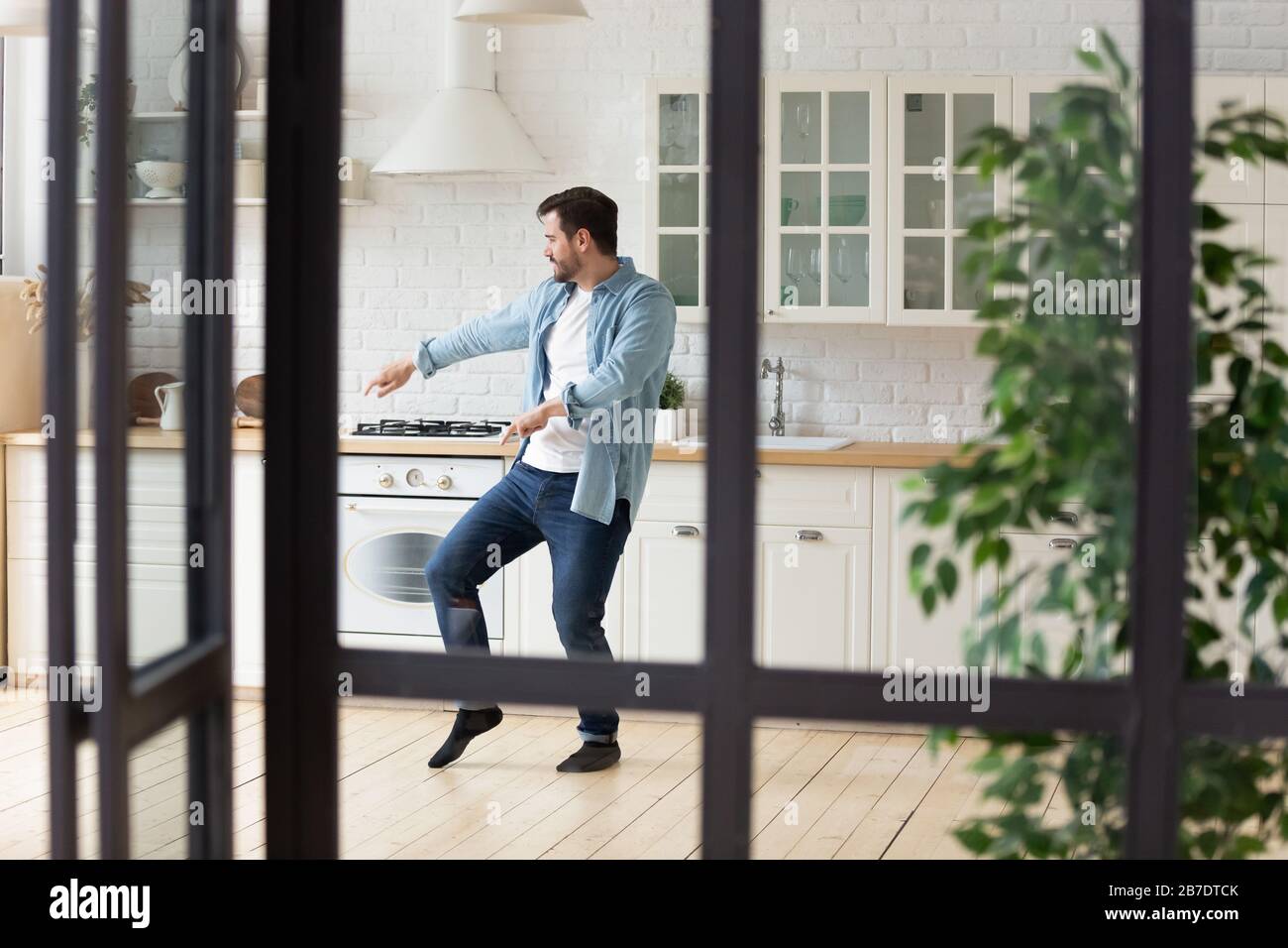Divertente uomo positivo ballare in cucina moderna da solo Foto Stock
