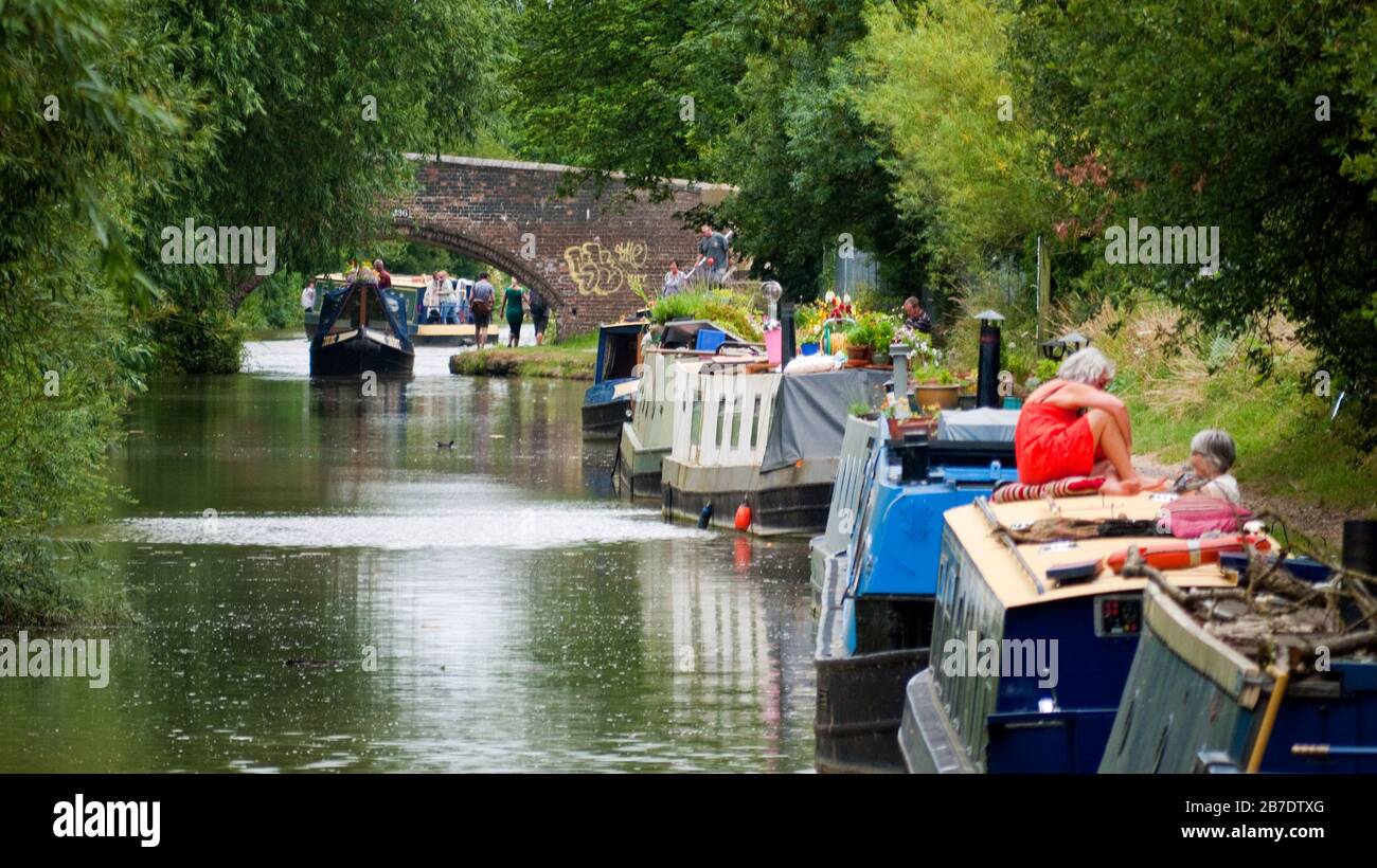Coloratissimi narrowboat ormeggiati lungo il canale di Oxford con ponte ad arco sul canale, vicino a Oxford, Inghilterra, Regno Unito, Gran Bretagna, Oxfordshire Foto Stock