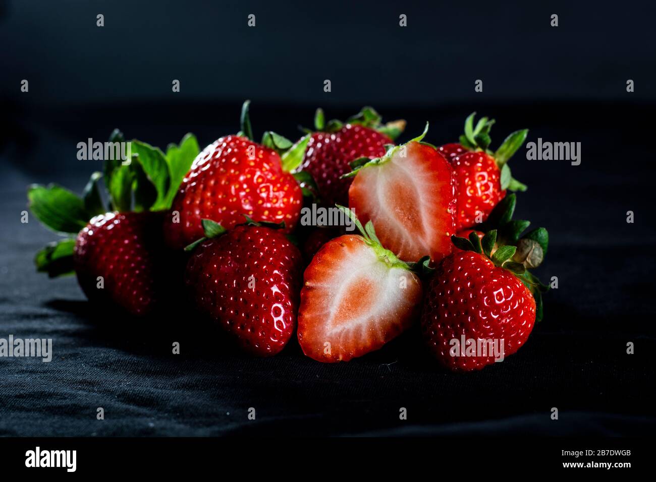 Bellissime fragole rosse con sfondo nero e pioggia leggera Foto Stock