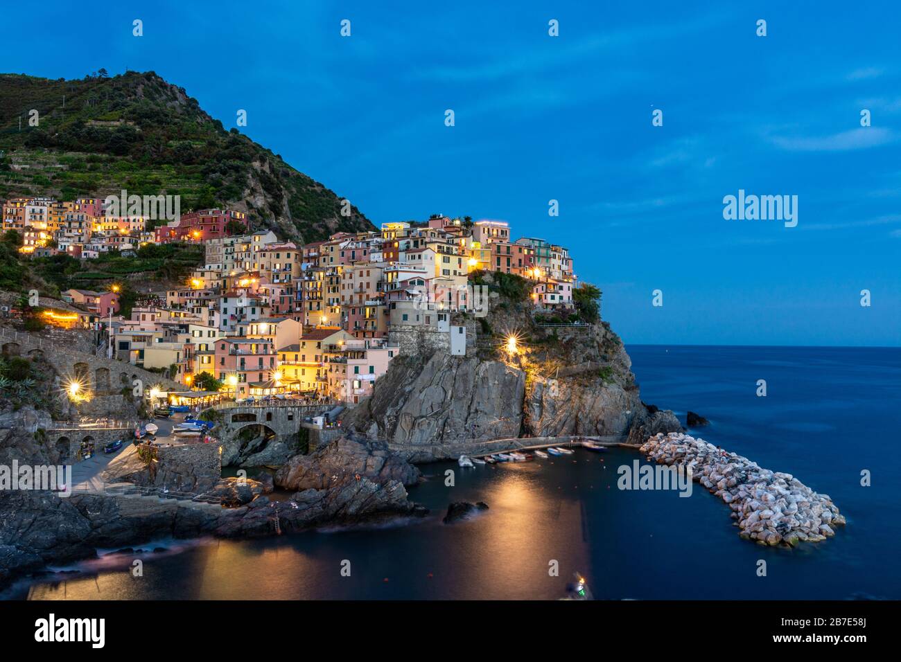 Manarola come uno dei villaggi delle cinque Terre durante l'ora blu con le luci Foto Stock