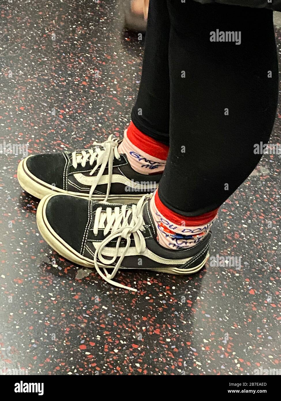 Gambe e piedi di un teen in piedi su un treno della metropolitana a Brooklyn, New York. Foto Stock