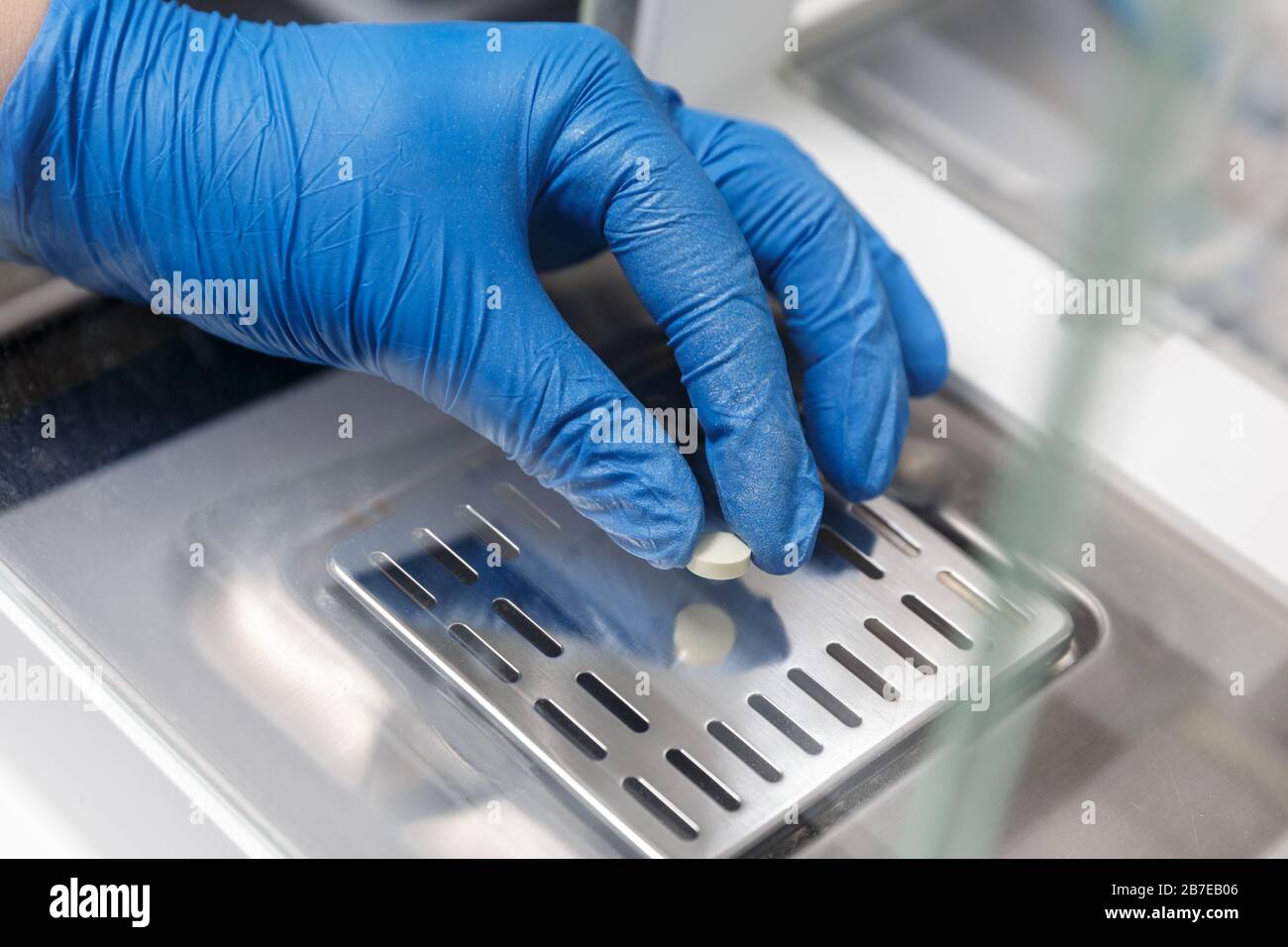 Farmacista in guanti per uso medico che pesano una nuova pillola in un laboratorio farmaceutico. Concetto di industria farmaceutica Foto Stock