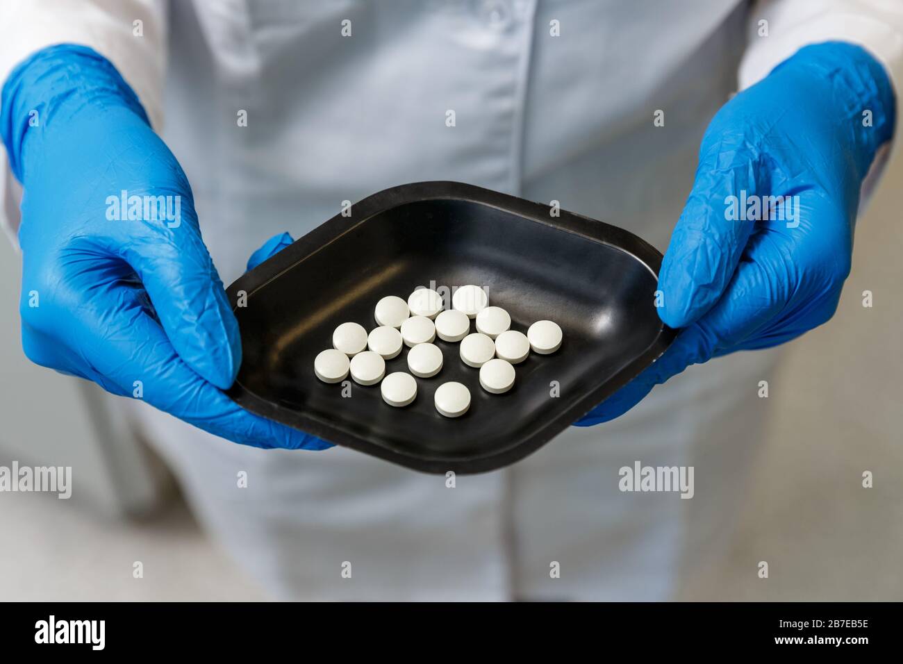 Farmacista in guanti blu per uso medico che tengono pillole di medicina di recente sviluppo in un laboratorio farmaceutico. Concetto di industria farmaceutica Foto Stock