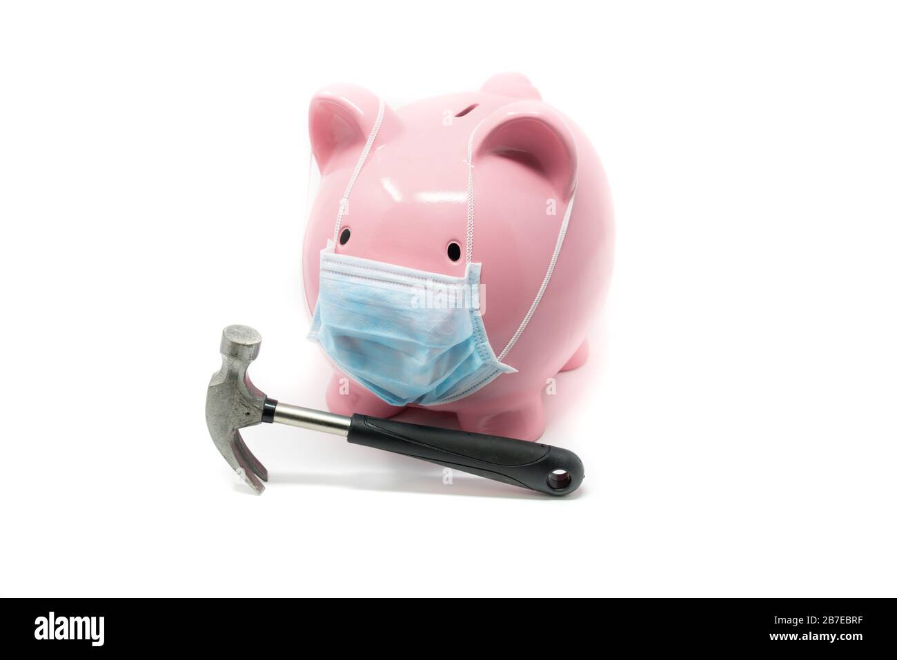 Piggybank con maschera chirurgica e martello, concetto dell'impatto di una pandemia nell'economia mondiale Foto Stock