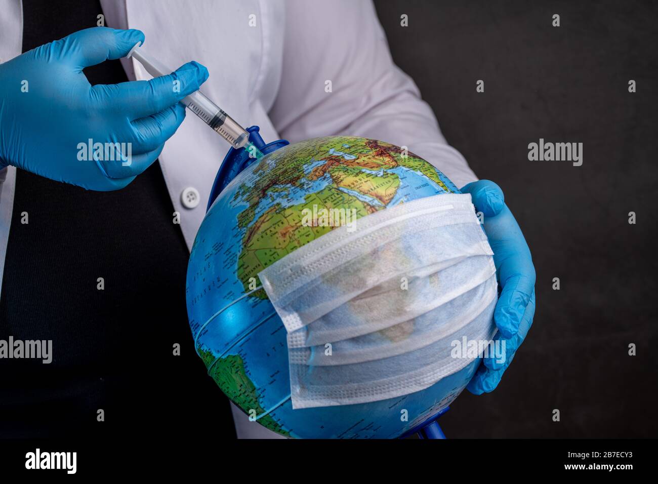 Medico che vaccina la terra a causa di coronavirus con guanti medici blu Foto Stock