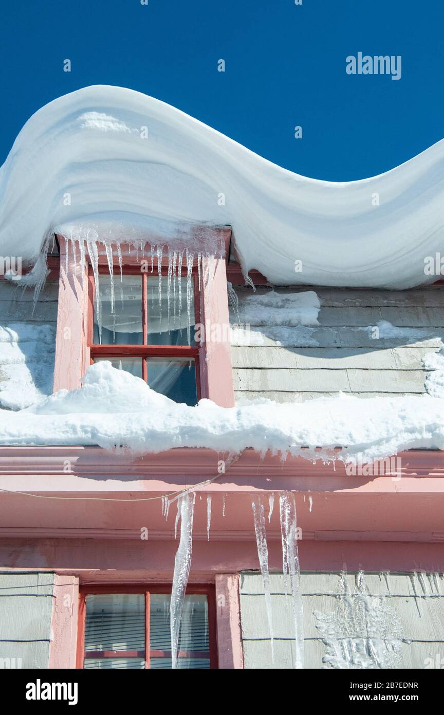 Casa Annapolis colorato il giorno di sole dopo beizzard con neve swirled e scivolato sul tetto gocciolando di ghiaccio. Foto Stock