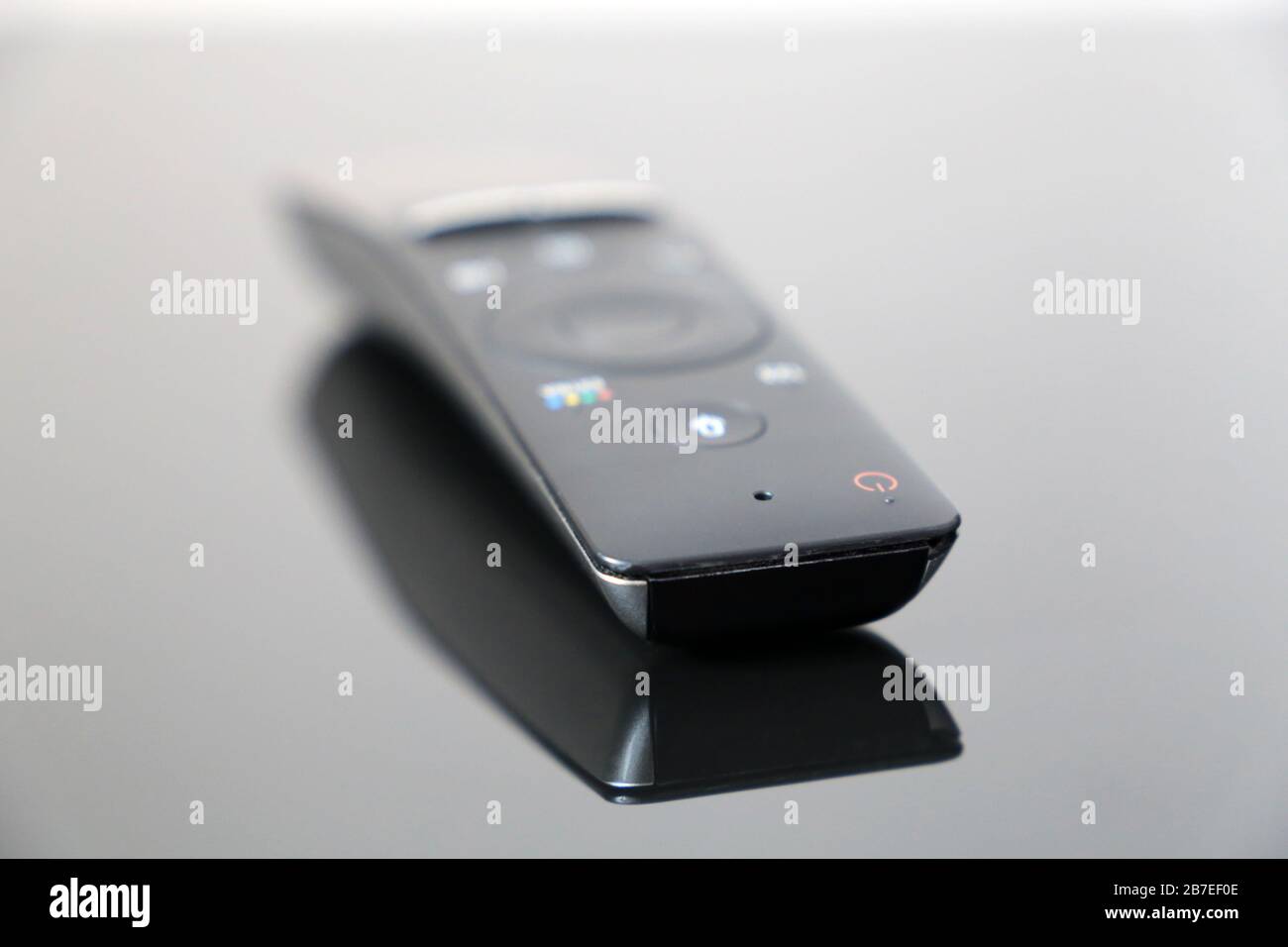 Telecomando TV con comando vocale su tavolo in vetro nero. Telecomando intelligente con ricerca Foto Stock