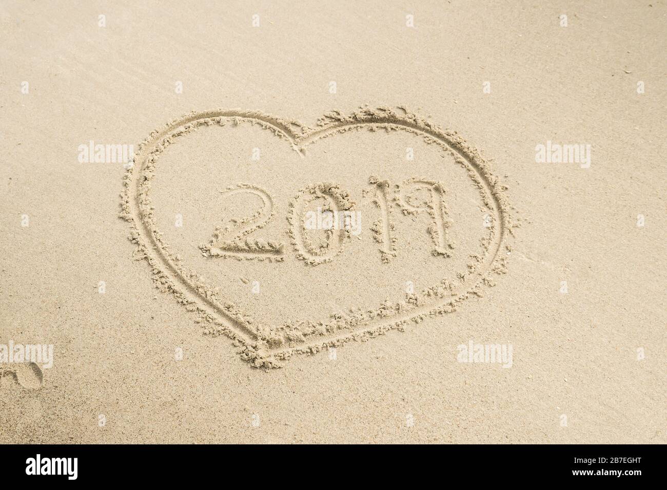 Forma di un cuore e 2019 scritto al suo interno una superficie di sabbia Foto Stock