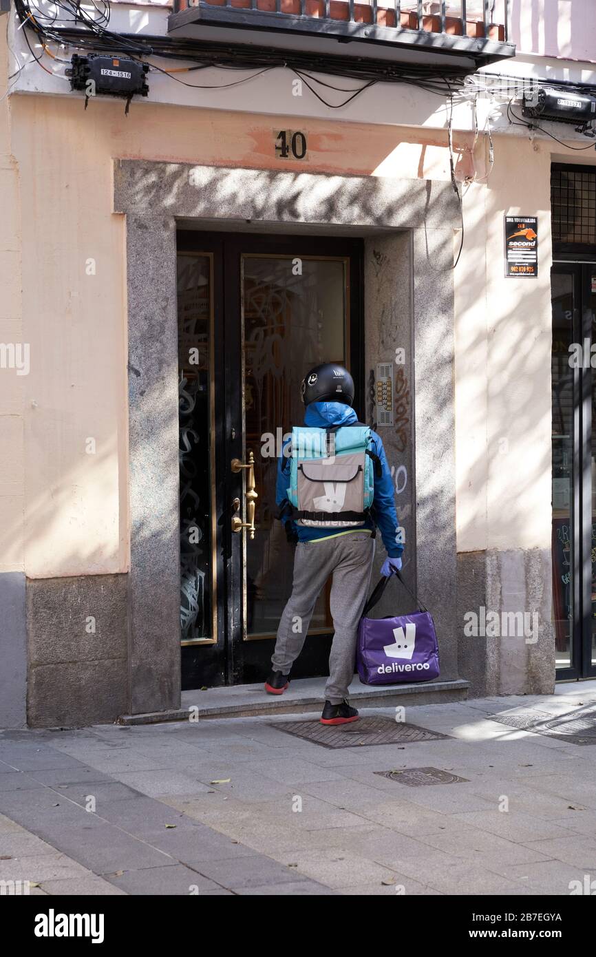 Un delivoo biker effettua una consegna in un edificio di appartamenti nel centro di Madrid durante lo stato di emergenza del virus corona Foto Stock