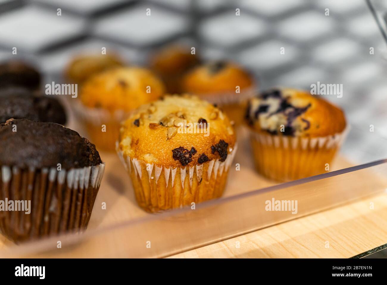 Macro di primo piano di muffin su vassoio da forno a buffet per colazione continentale al mattino in hotel motel o ufficio e rivestimenti di carta per prodotti da forno al cioccolato Foto Stock