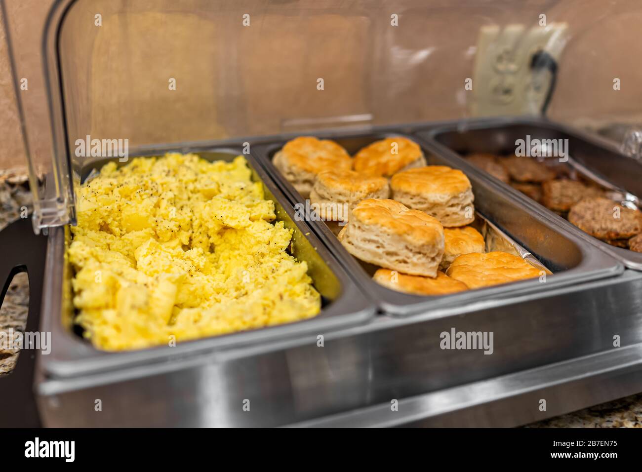 Selezione di piatti caldi a buffet con piatti a base di uova strapazzate, biscotti e salsicce a banchetto, matrimonio o ristorante all'interno per la colazione continentale mattutina Foto Stock