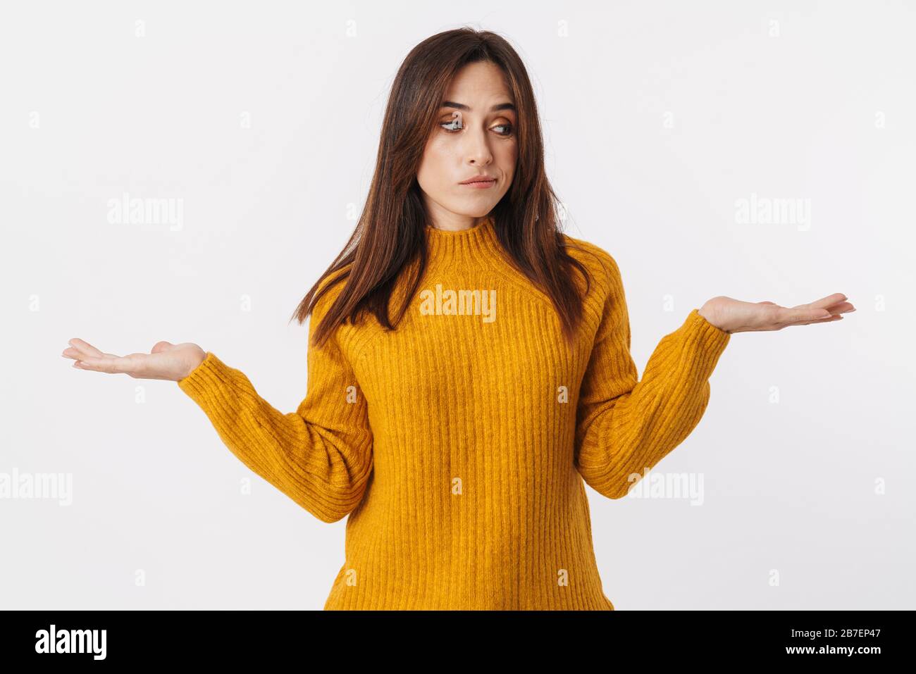 Immagine di bella donna bruna adulto che indossa maglione esitante e gettando le mani isolato su sfondo bianco Foto Stock