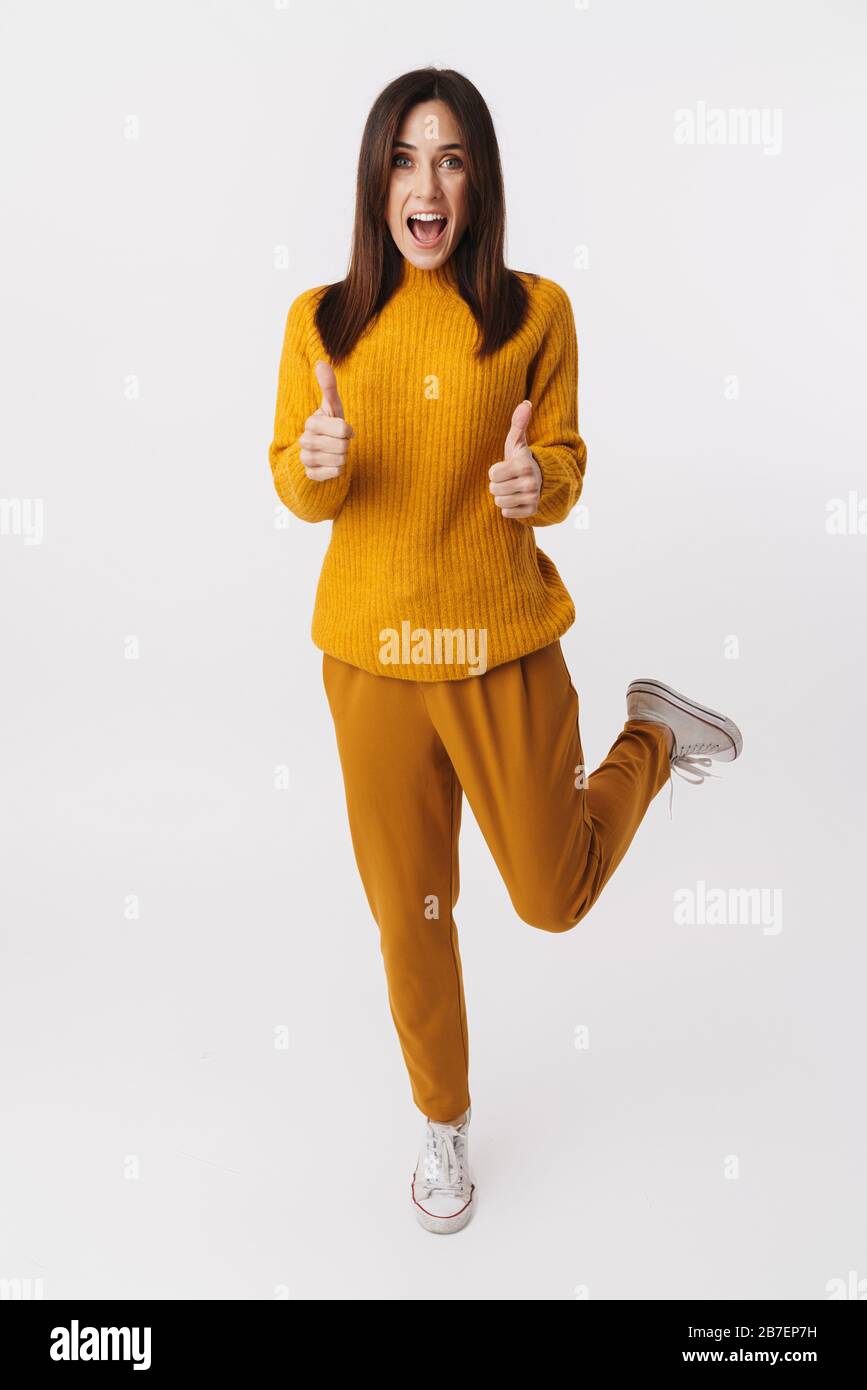 Immagine a tutta lunghezza di bella donna bruna adulto sorridente e gesturante pollice su isolato su sfondo bianco Foto Stock