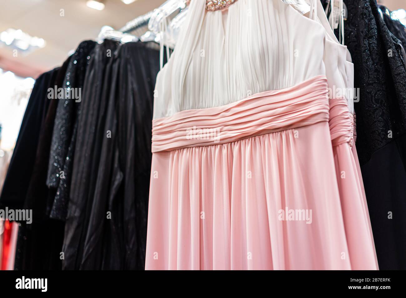 Abito femminile formale in stile europeo bianco e rosa appeso sul appendiabiti in negozio di abbigliamento boutique in Europa Foto Stock
