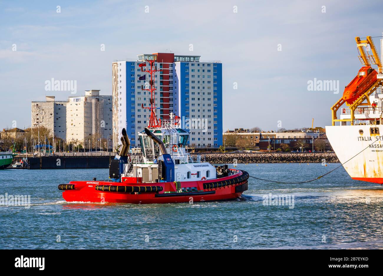 Barca rossa di rimorchiatore Marksman che guida una nave al porto da Gosport in porto di Portsmouth, Solent, Hampshire, costa meridionale Inghilterra Foto Stock