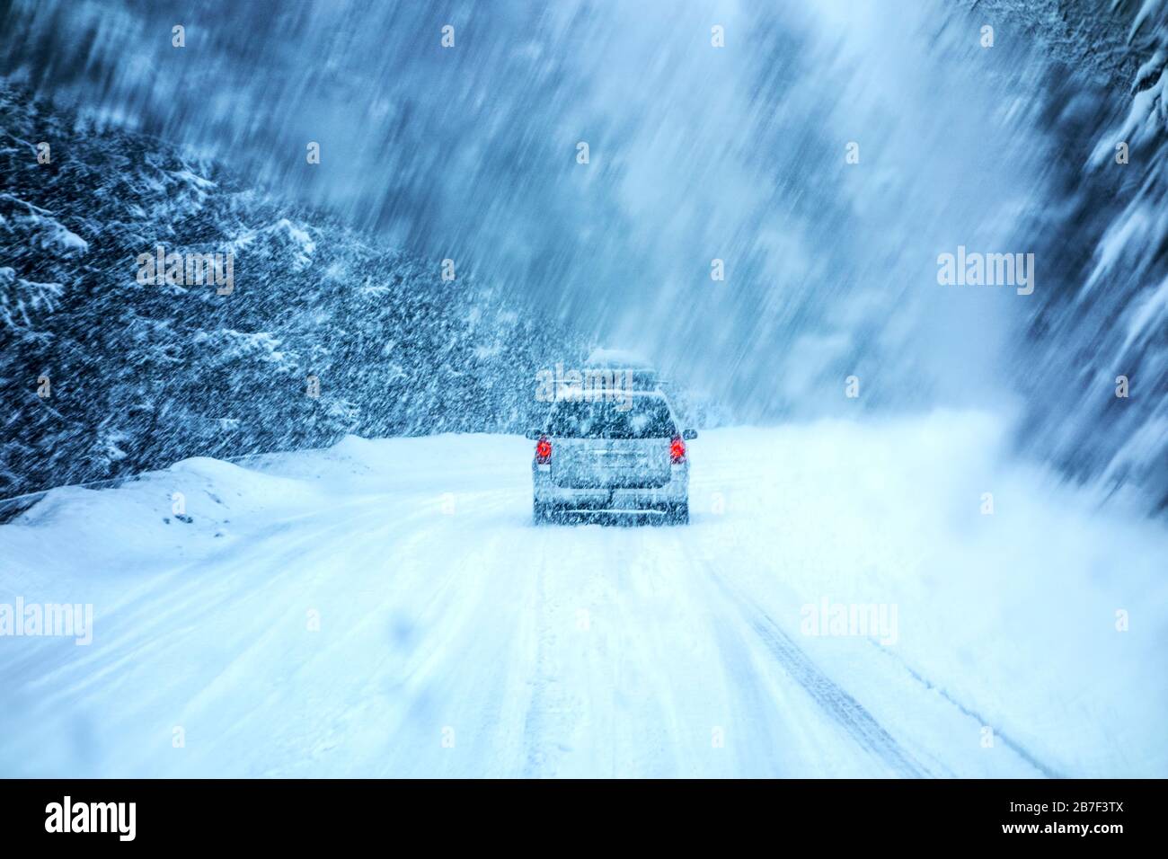 Guida in auto durante la tempesta di neve invernale, attraversata da un parabrezza coperto da fiocchi di neve sfocati. Foto Stock