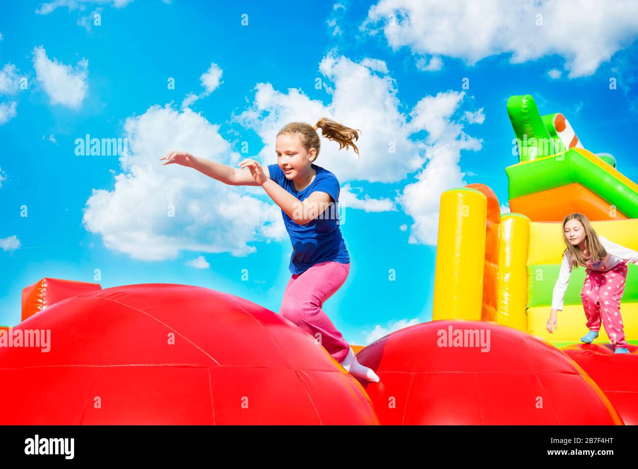 Felice bambine avente un sacco di divertimento durante il salto dal giunto a sfera su un gonfiare il castello. Foto Stock