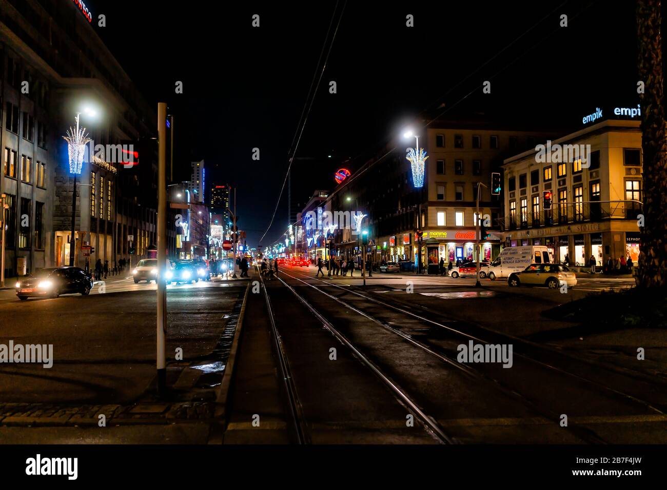 Varsavia, Polonia - 17 dicembre 2019: Via Jerozolimskie di notte nella città vecchia di Warszawa con persone che camminano nei negozi con i tram tracce, c Foto Stock