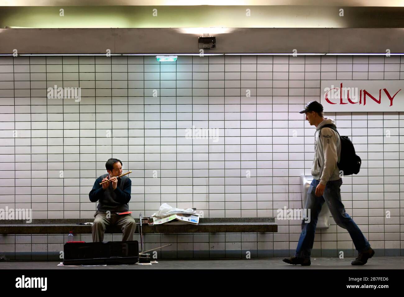 Un uomo cammina da un busker che si esibisce nella stazione della metropolitana Cluny la Sornbonne, Left Bank, Parigi, Francia, Europa, colore Foto Stock