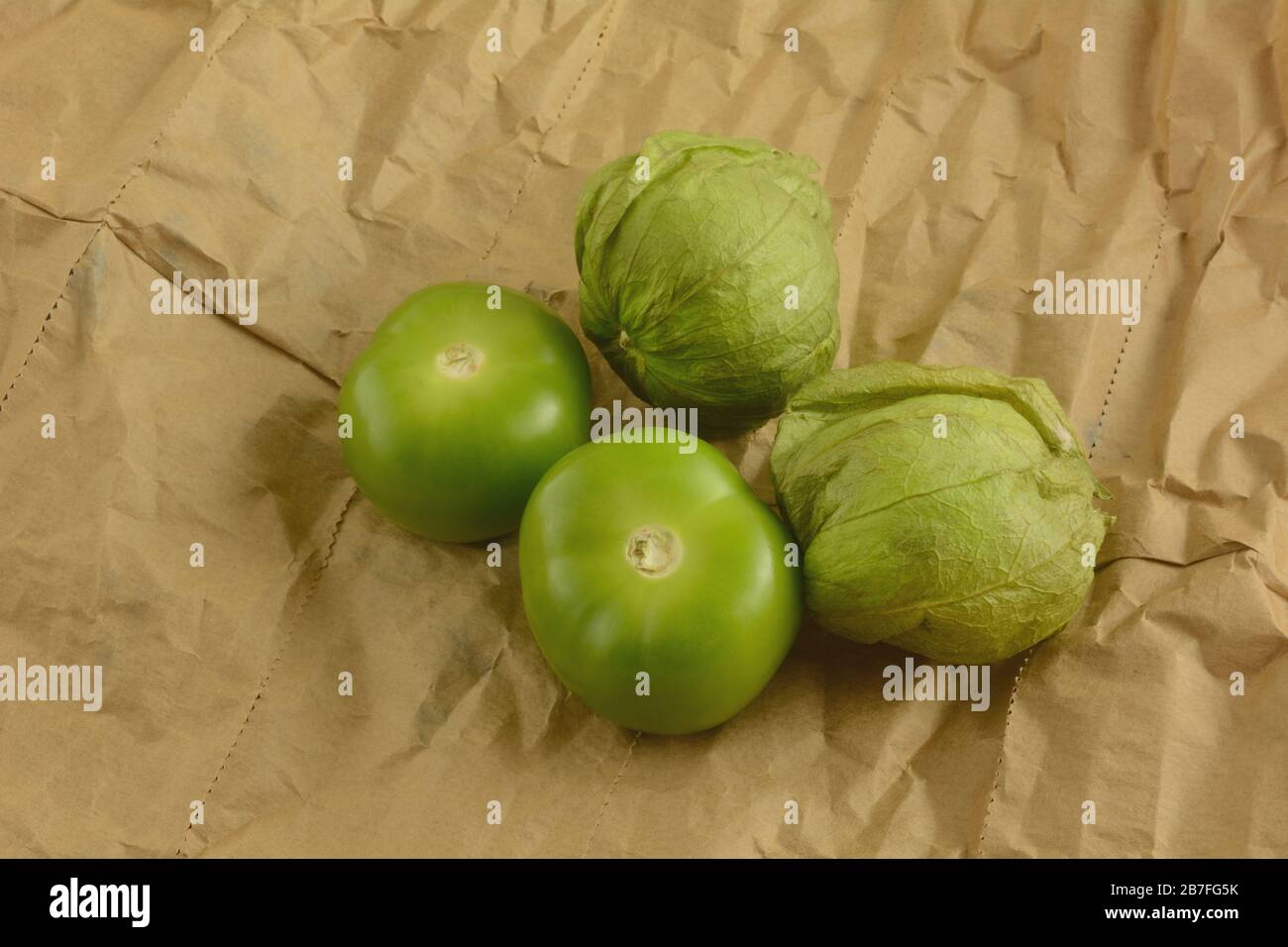 Tomatillos crudi freschi con e senza bucce su carta marrone ecologica Foto Stock