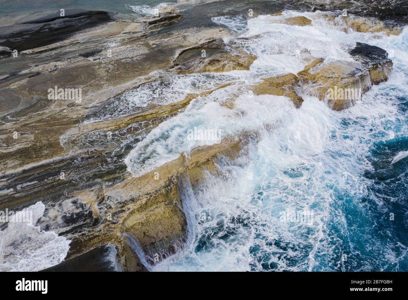 Cattura aerea delle onde del Pacifico che si rivaleggiano sullo sperone roccioso lungo la costa di Biri Island, Samar del Nord, Filippine Foto Stock