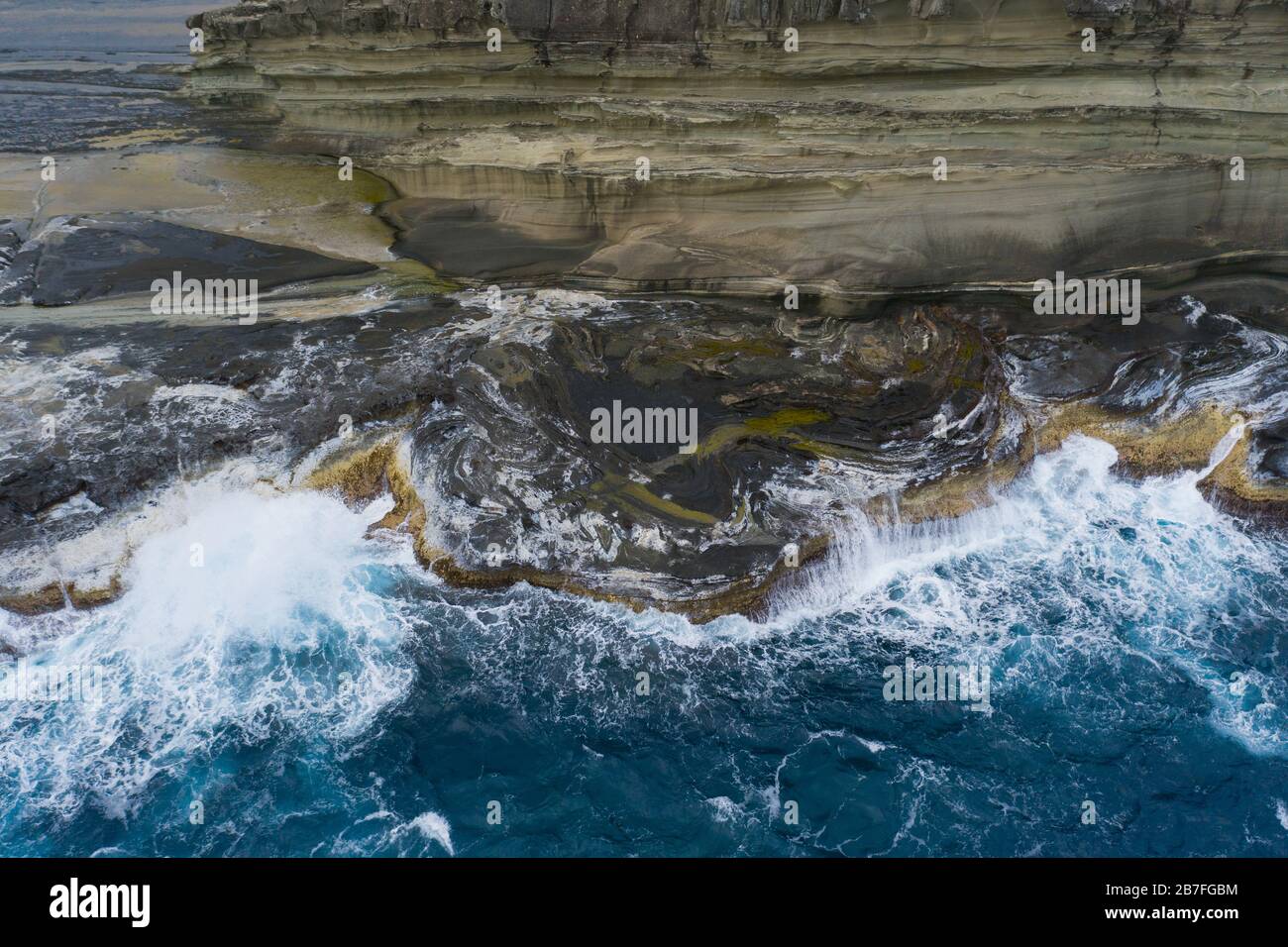 Cattura aerea delle onde del Pacifico che si rivaleggiano sullo sperone roccioso lungo la costa di Biri Island, Samar del Nord, Filippine Foto Stock