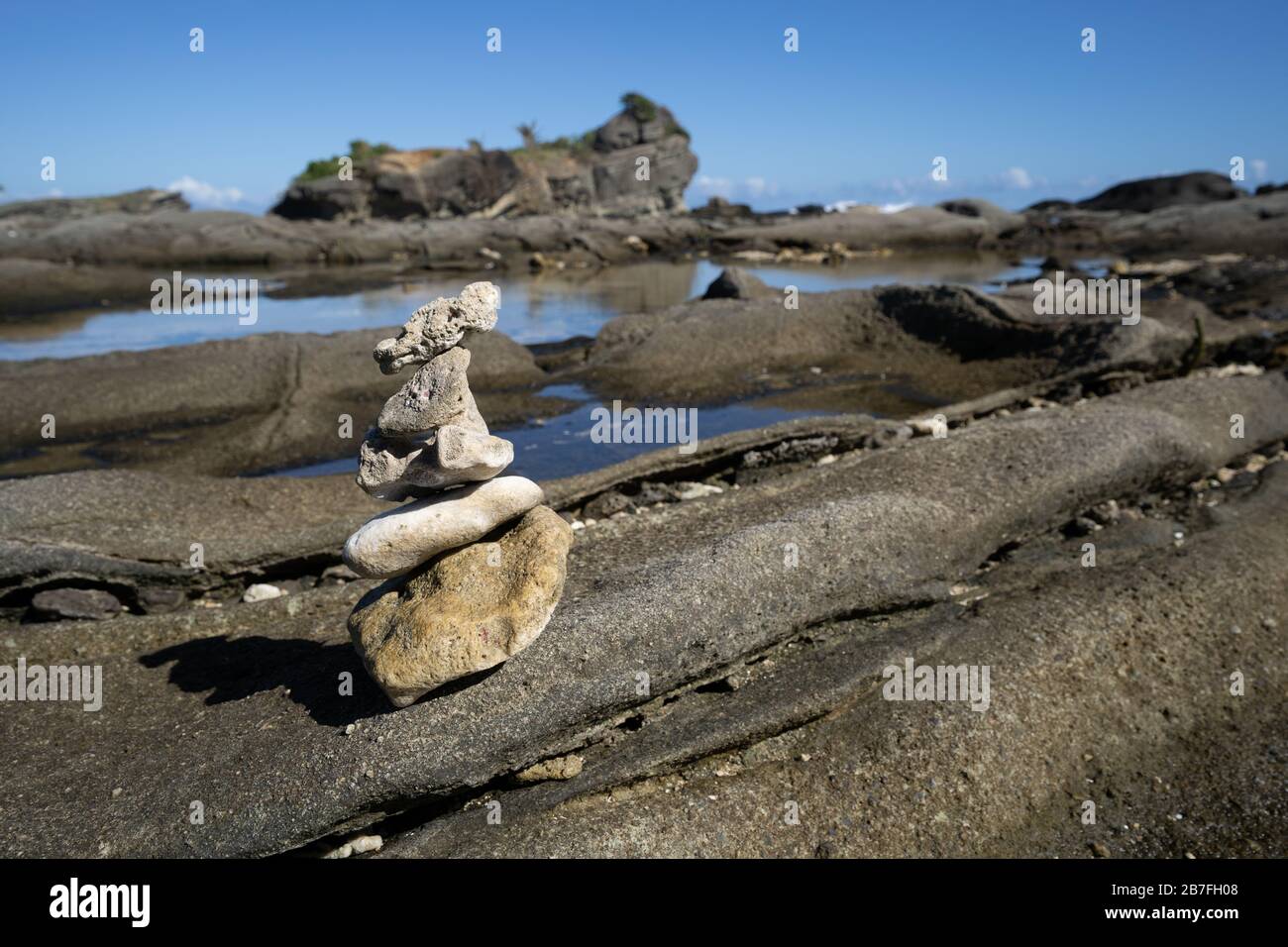 Pietre accatastate in un mucchio di Cairn su uno sperone roccioso lungo una costa del Pacifico, Isola di Biri, Filippine Foto Stock
