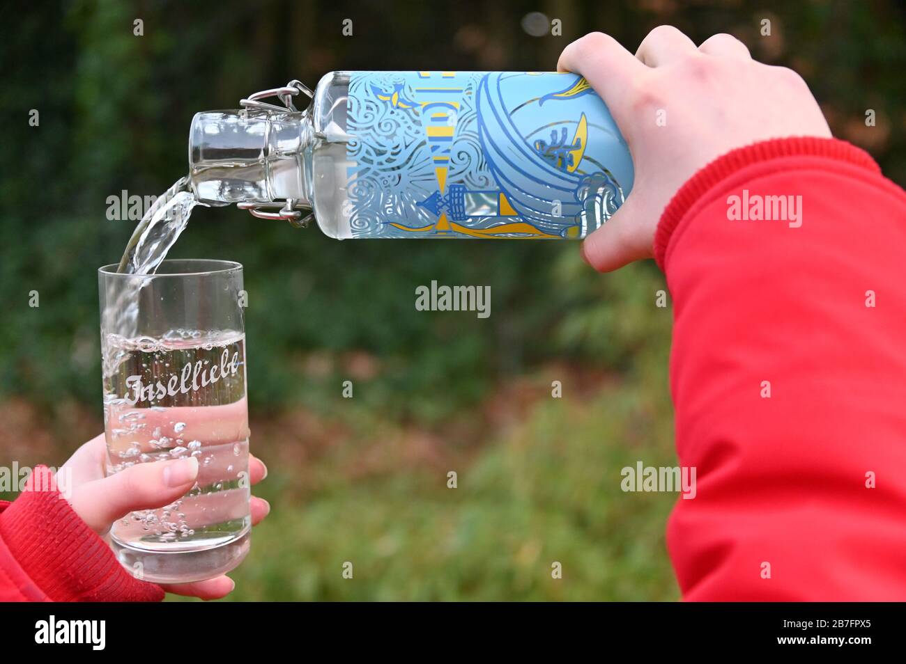 11 marzo 2020, Schleswig-Holstein, Westerland/Sylt: ILLUSTRAZIONE - acqua di rubinetto da una 'bottiglia di stilo' disponibile presso l'ufficio informazioni turistiche è riempita in un vetro con l'iscrizione 'Inselliebe'. Il 22 marzo, Sylt diventa ufficialmente uno dei 12 distretti idrici a livello nazionale dell'associazione ''a tip: TAP'', che si impegna per l'aumento del consumo di acqua di rubinetto. (A dpa 'acqua turnaround sull'isola - Sylt vuole promuovere il consumo di acqua di rubinetto') Foto: Carsten Rehder/dpa Foto Stock