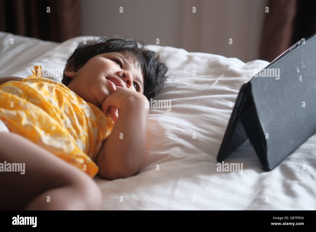 Primo piano del bambino utilizzare un tablet digitale a letto Foto Stock
